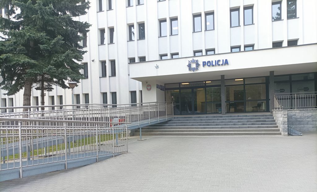 plac przed budynkiem Komendy Miejskiej Policji w Zamościu, prowadzące do wejścia budynku schody oraz podjazd dla wózków 
