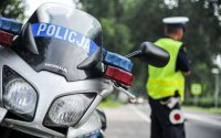 motocykl policyjny i stojący tyłem policjant ruchu drogowego