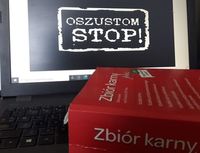 laptop, wyświetlony na ekranie napis Oszustom Stop, na klawiaturze położona książka zbiór karny