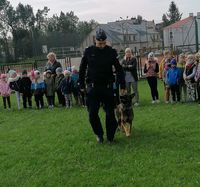 policjant podczas spotkania z przedszkolakami w czasie pokazywania elementów tresury psa służbowego